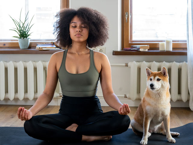 FEMME FAISANT DU YOGA AVEC SOIN CHIEN