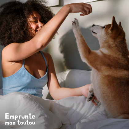 JEUNE FEMME JOUANT AVEC SON CHIEN SUR LE LIT