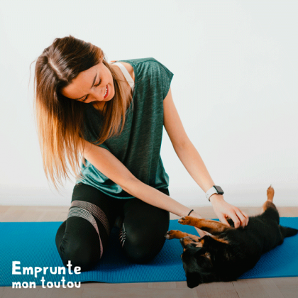 jeune femme massant le ventre de son chien sur un tapis de yoga