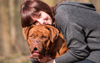 femme serrant un dogue de bordeaux dans ses bras