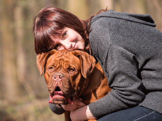 femme serrant un dogue de bordeaux dans ses bras