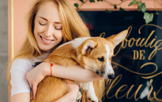 FEMME PORTANT UN CHIEN DE RACE CORGI DANS SES BRAS