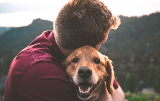 homme serrant un chien dans ses bras