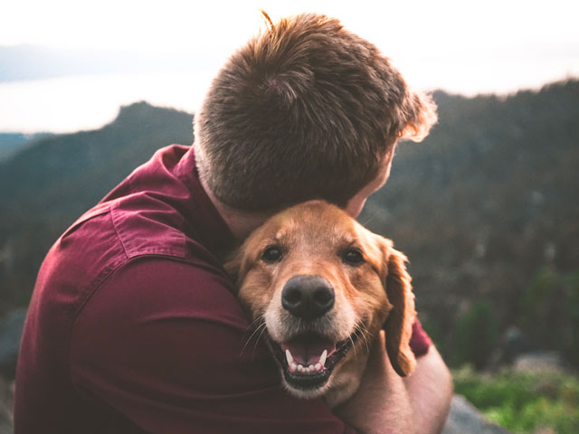 homme serrant un chien dans ses bras