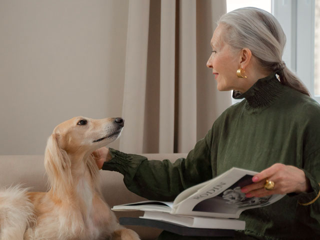 femme âgée caressant un chien de type lévrier