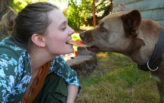 femme mangeant une tranche de pastèque avec son chien