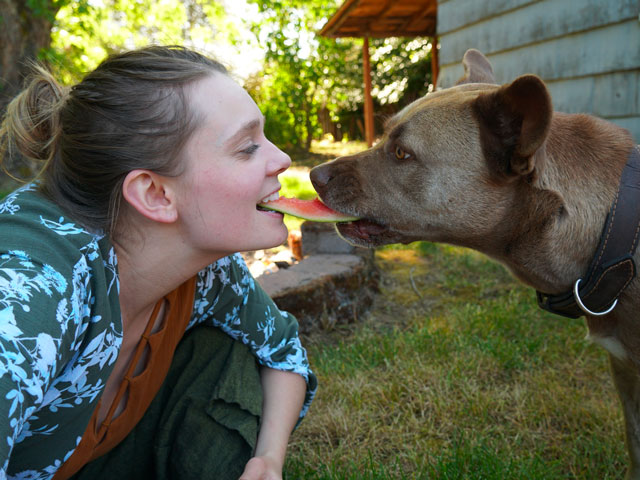 femme mangeant une tranche de pastèque avec son chien